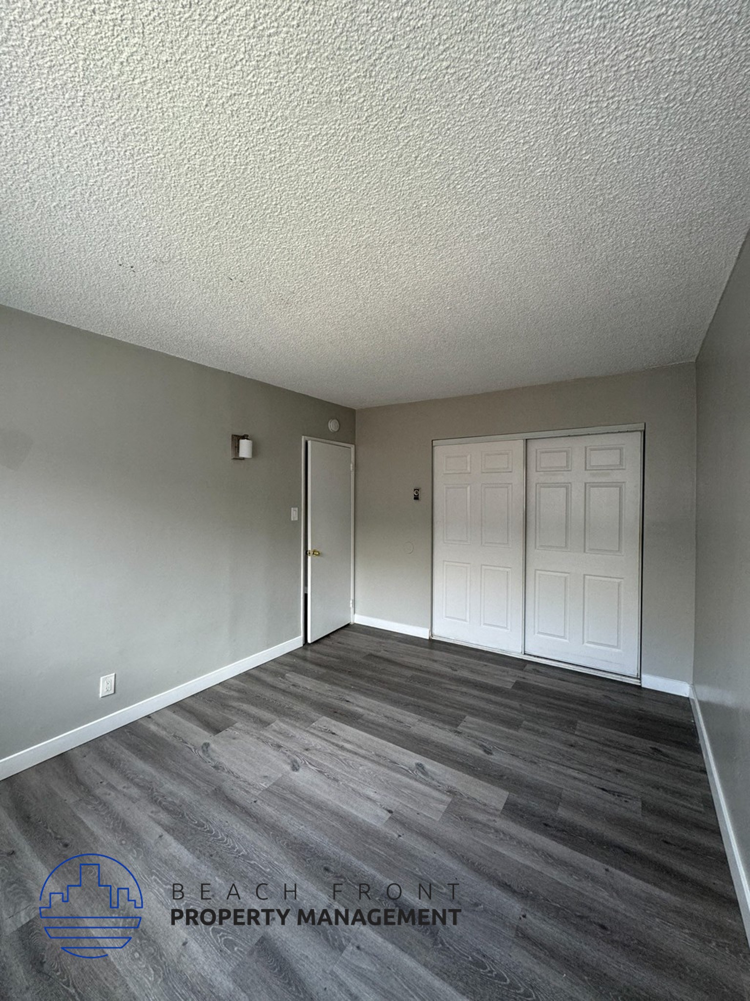 an empty living room with a white door and wood floors